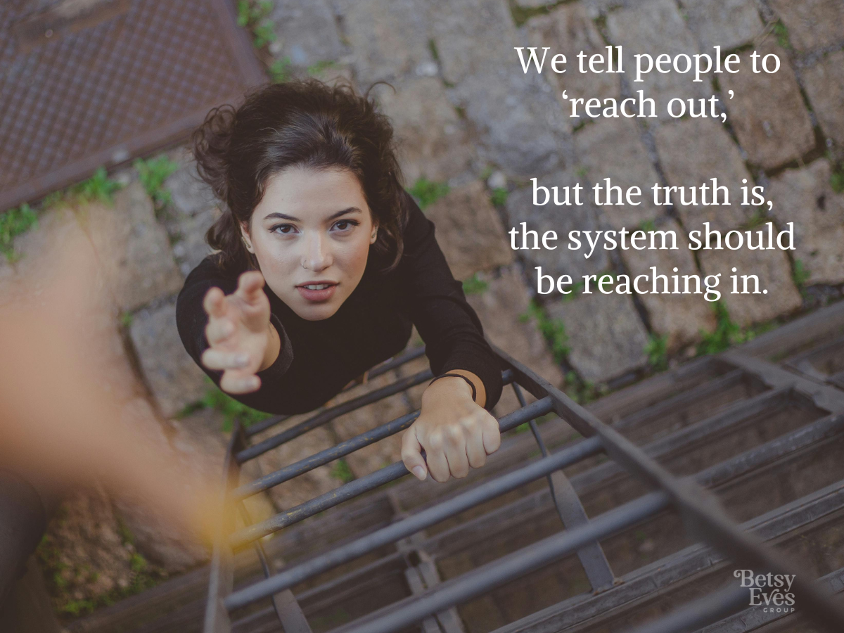 Image of a hand reaching down to a woman reaching up while climbing a ladder on the side of a building.   Text overlay reads: We tell people to "reach out," but the truth is, the system should be reaching in.